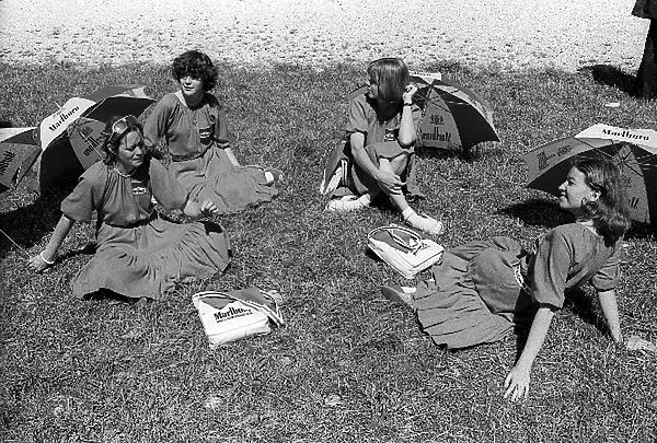 Formula One World Championship: The Marlboro girls take a rest on the grass area in the pitlane as the blistering heat continued to bless France