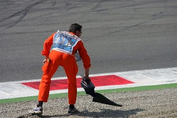 Formula One World Championship: A marshal collects a bit of broken body work from the first chicane