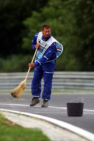 Formula One World Championship: Marshal sweeps the circuit after incident involving Jenson Button Honda RA106