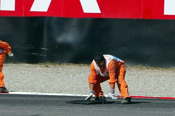 Formula One World Championship: Two marshals retrieve a piece of speed-hump from the track at the second chicane