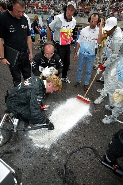 Formula One World Championship: McLaren mechanics clean up an oil leak on the grid