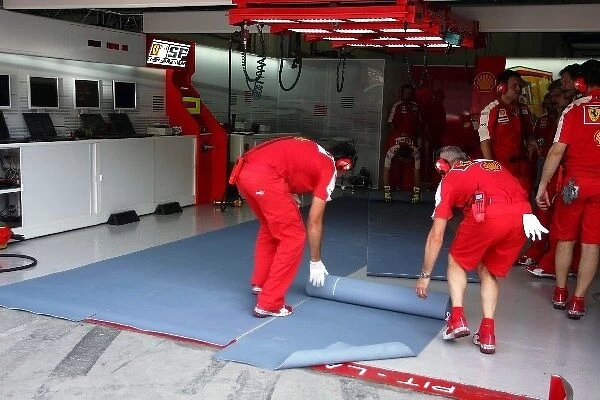 Formula One World Championship: Mechanics roll out the rubber mats after the Ferrari F2009 of Kimi Raikkonen Ferrari stops after a possible KERS
