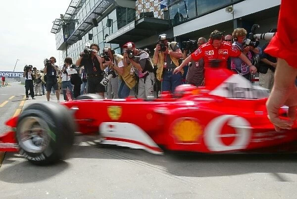 Formula One World Championship: Media and photographers crowd the Ferrari garage during qualifying as Michael Schumacher Ferrari F2002 leaves