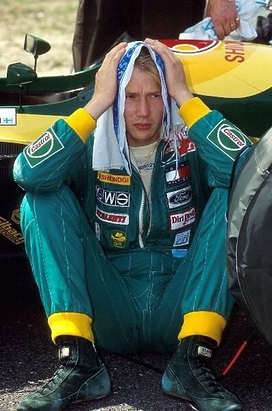 Formula One World Championship: Mika Hakkinen Lotus107 attempts to find shelter from the hot and sunny weather on the grid