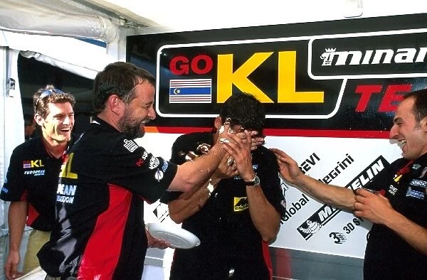 Formula One World Championship: Minardi team owner Paul Stoddart helps Alex Yoong celebrate his 26th birthday. Mark Webber, left, watches