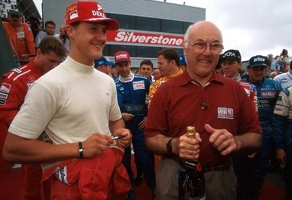 Formula One World Championship: Murray Walker is presented by Michael Schumacher with a bottle of Champagne signed by the Formula One drivers