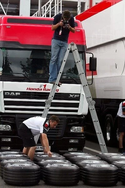 Formula One World Championship: Photographer Clive Rose gets up a ladder to shoot a BAR mechanic with Michelin tyres