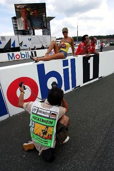 Formula One World Championship: A photographer takes pictures of a woman on the pit wall