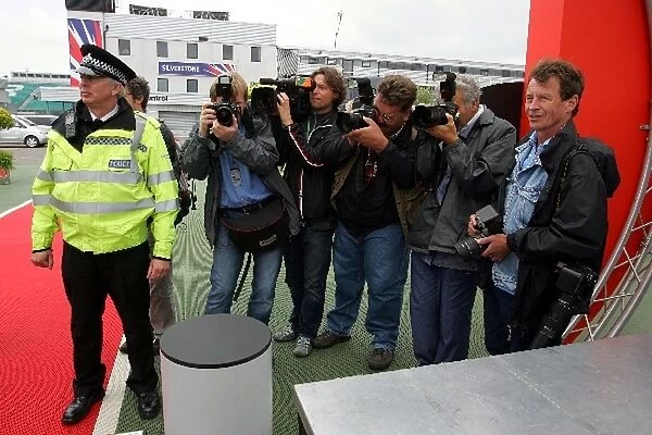 Formula One World Championship: Photographers wait to capture the moment as a Policeman checks the bags of an F1 personality