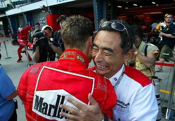 Formula One World Championship: Pole position winner Michael Schumacher Ferrari is embraced by Hiroshi Yasukawa Bridgestone Director of Motorsports