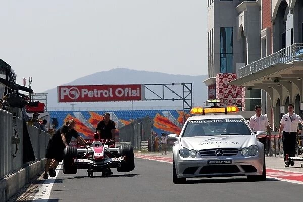 Formula One World Championship: The safety car passes the Super Aguri F1 Team mechanics as they push a car down the pitlane