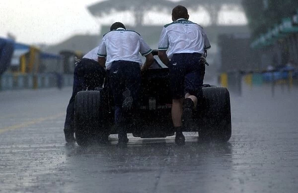 Formula One World Championship: Sauber mechanics push a car through the rain