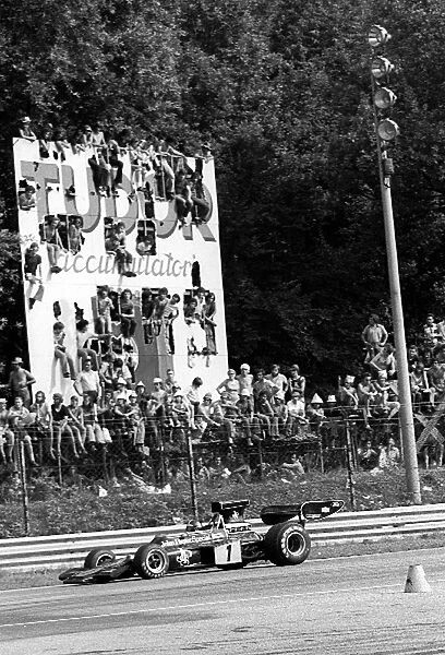 Formula One World Championship: Second placed Emerson Fittipaldi Lotus 72D passes a Tudor Batteries advertising hoarding, converted into a grandstand