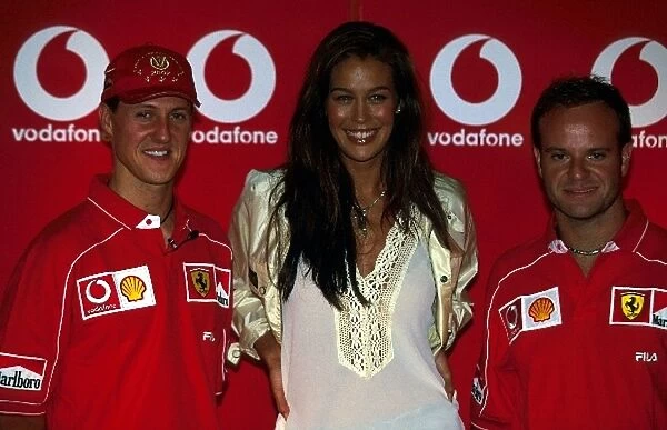 Formula One World Championship: Second placed Michael Schumacher Ferrari; the face of Vodafone Megan Gale; race winner Rubens Barrichello Ferrari