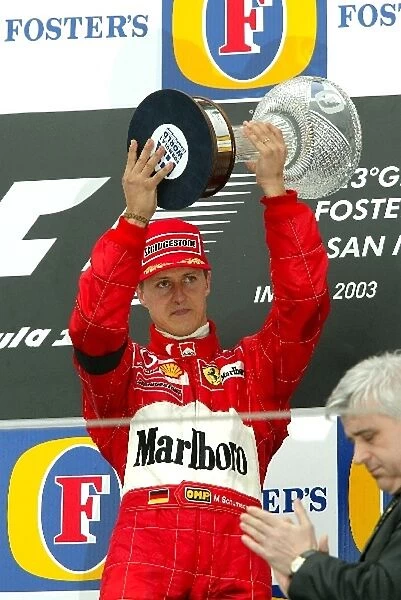 Formula One World Championship: A sombre Michael Schumacher Ferrari F2002 accepts his race winning trophy on the podium, sadly on the same day