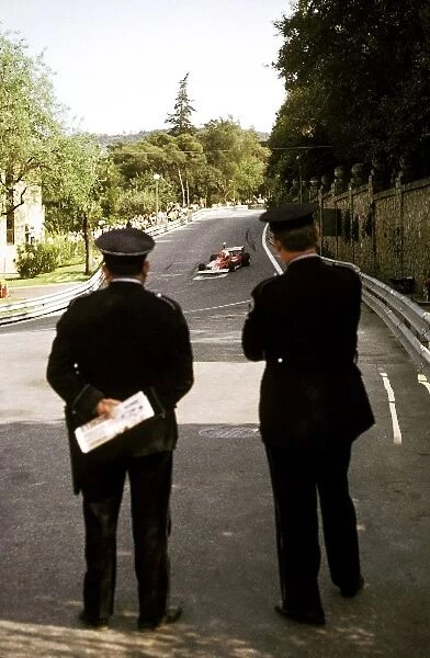 Formula One World Championship: Two Spanish policemen watch Niki Lauda Ferrari 312T circulate around the circuit during practice