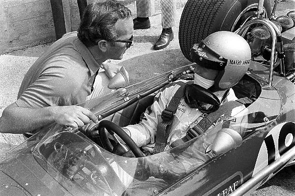 Formula One World Championship: Team Lotus owner Colin Chapman, left, chats with Mario Andretti, in car, Lotus 49B who qualified in 21st place