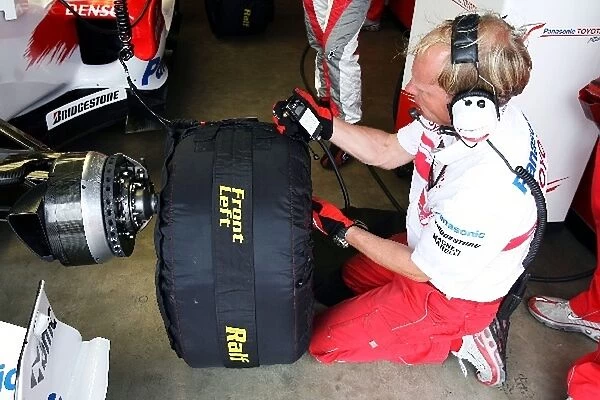 Formula One World Championship: Toyota engineer waits to put a wet tyre on the Toyota TF107 of Ralf Schumacher Toyota