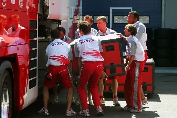 Formula One World Championship: Toyota mechanics lift a very heavy crate into their transporter