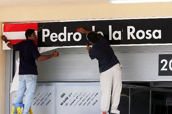 Formula One World Championship: Track workers replace the ofJuan Pablo Montoya McLaren over the pit garage with his replacement Pedro de la Rosa McLaren