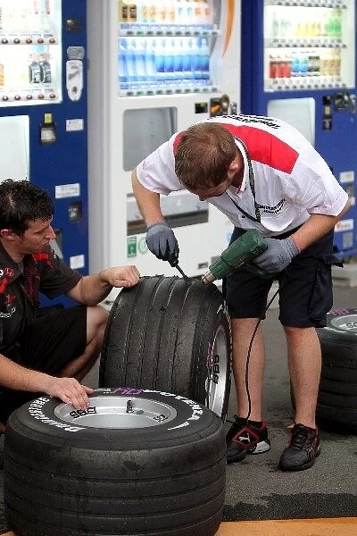 Formula One World Championship: A Tyre technician scrapes excess rubber off a tyre