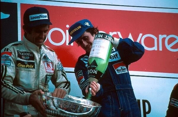 Formula One World Championship: Winner Alain Prost empties the champagne into the trophy held by 2nd placed Carlos Reutemann