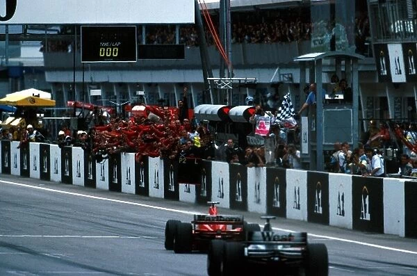 Formula One World Championship: Winner Eddie Irvine Ferrari F399 takes the flag just ahead of David Coulthard