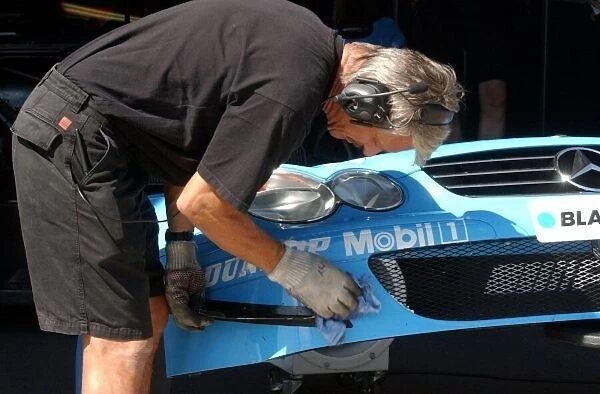 Mercedes-Benz engineer cleaning the front cover of the car of Stefan Mucke (GER)