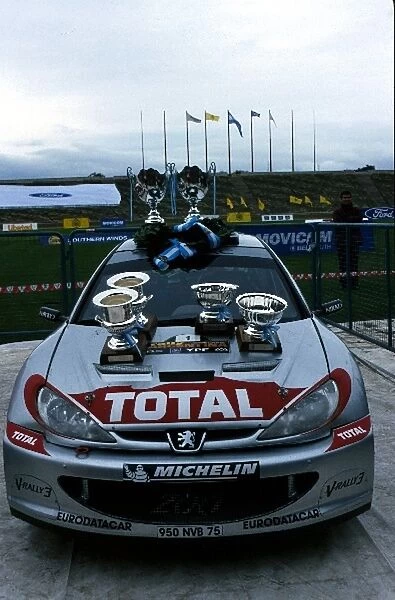 World Rally Championship: The Peugeot 206 WRC of Richard Burns proudly displays the silverware that would later be awarded to Carlos Sainz and Ford