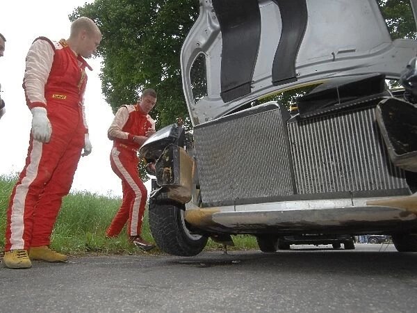 World Rally Championship: Yvgeny Novikov looks on as his co-driver attempts a temporary repair to get them to service