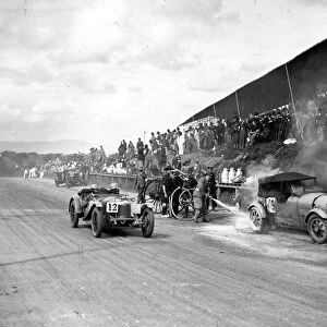 1928 RAC Tourist Trophy: Malcolm Campbell on fire in the pit lane. Ian MacDonald passes in his Riley