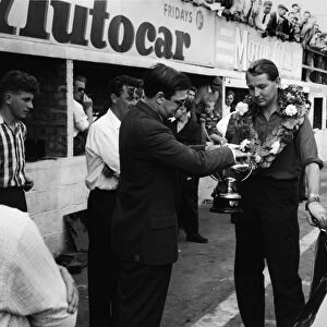 1958 British Saloon Car Championship: Tommy Sopwith, Jaguar 3. 4, 1st position, presented with the Class D winners trophy in the pit lane, portrait