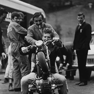 1965 Pau Grand Prix: Jochen Rindt, 1st position, on a moped with Charlie Crighton-Stuart and Jackie Stewart looking on, portrait