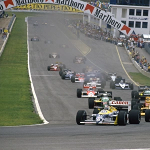 1987 Spanish Grand Prix: Nelson Piquet and teammate Nigel Mansell lead Ayrton Senna into Curva Expo at the start