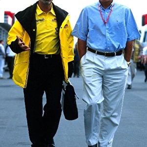 Formula One World Championship: Eddie Jordan, Jordan Grand Prix team owner, walks in discussion with Jacques Villeneuves manager Craig Pollock