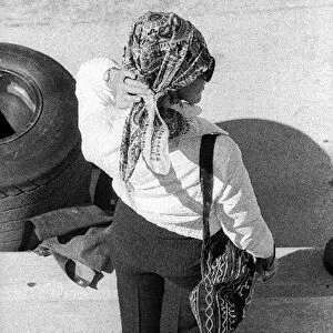 Formula One World Championship: Helen Stewart, wife of Jackie Stewart Tyrrell, uses a tyre to get a better view of the circuit during practice