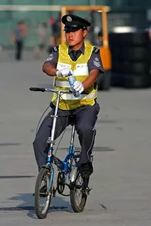 Formula One World Championship: Circuit security guard on a bicycle in the paddock